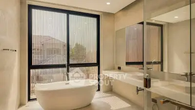 Luxurious bathroom with freestanding bathtub and large window offering natural light.