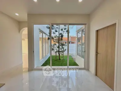Modern interior with large glass doors opening to a small green courtyard.