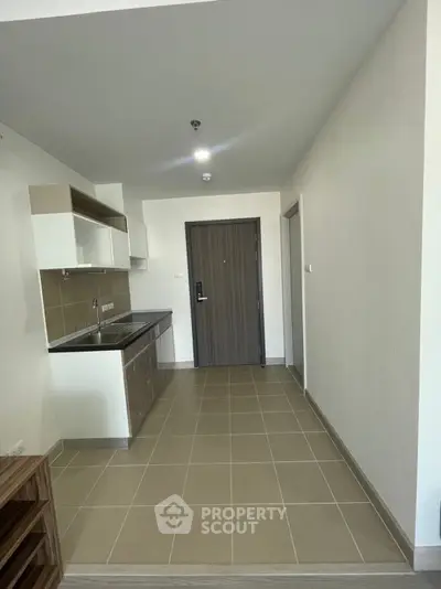 Modern minimalist kitchen with sleek cabinetry and tiled flooring in a compact apartment.