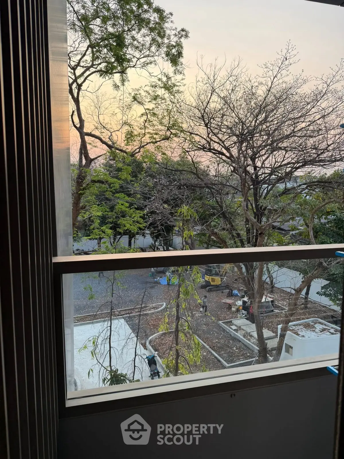 Scenic view from a window overlooking a serene outdoor area with trees and sunset.