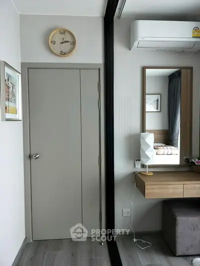 Modern bedroom with stylish decor and air conditioning, featuring a wall clock and mirror.