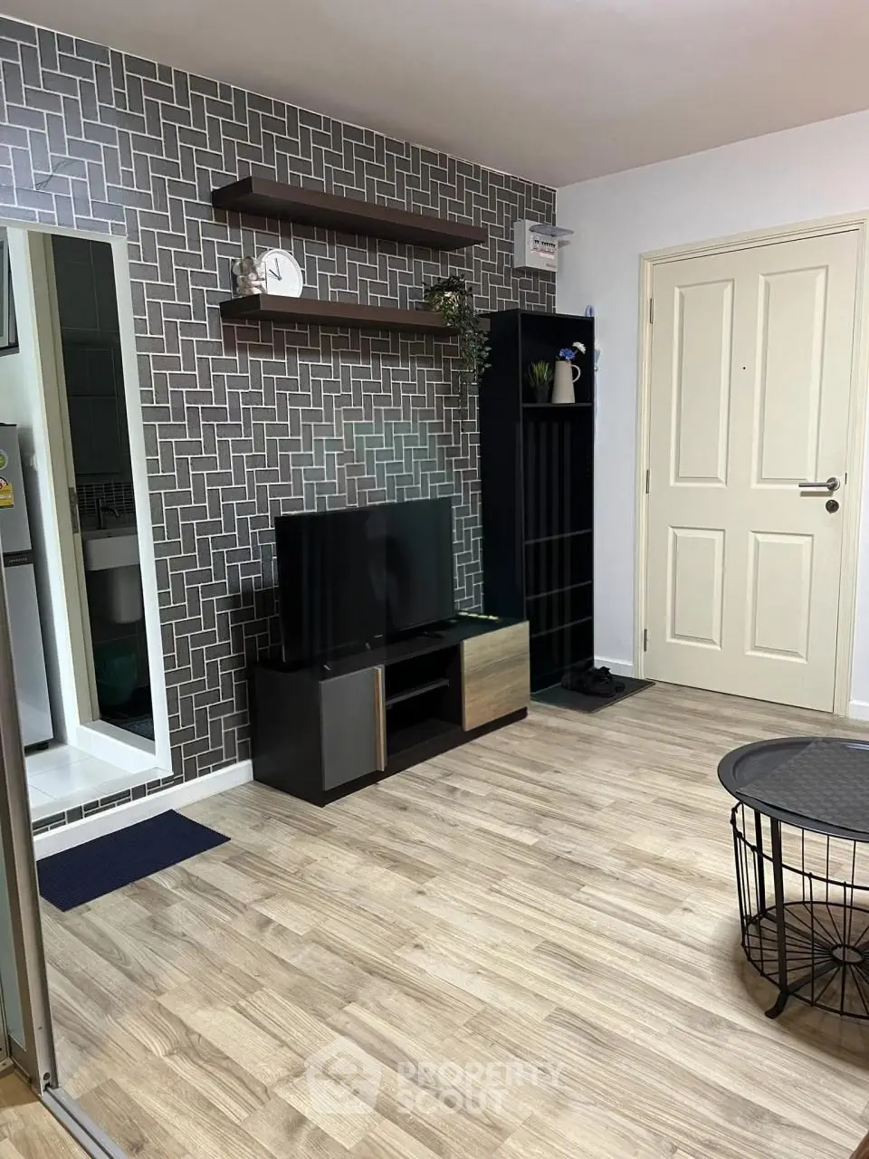 Modern living room with stylish decor and sleek furniture, featuring a TV and contemporary shelving.