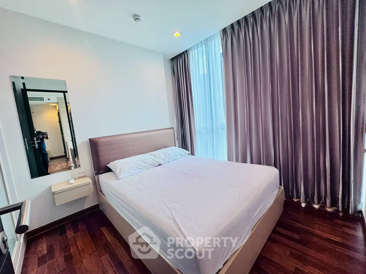 Modern bedroom with large window and elegant curtains in a stylish apartment.