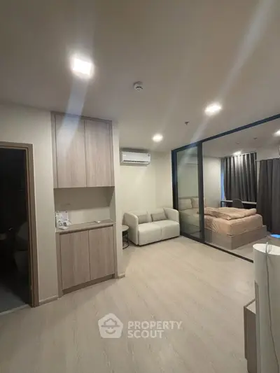 Modern apartment interior with open living room and bedroom, featuring sleek wooden flooring and contemporary furniture.