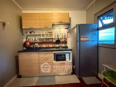 Modern kitchen with sleek cabinets, stainless steel fridge, and built-in microwave in cozy apartment.