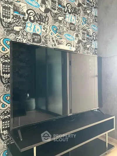 Modern living room with stylish graffiti wallpaper and sleek flat-screen TV.