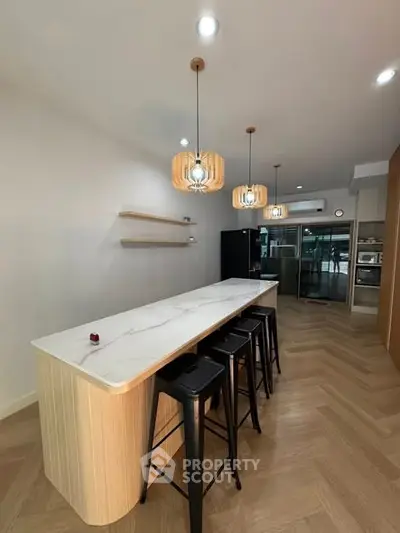 Modern kitchen with sleek island and stylish lighting, featuring open layout and contemporary appliances.