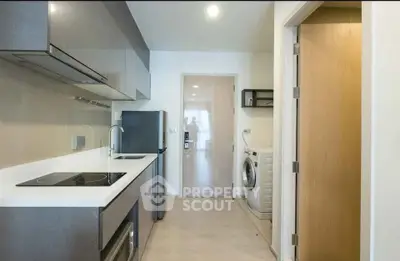 Modern kitchen with sleek appliances and washing machine in compact layout