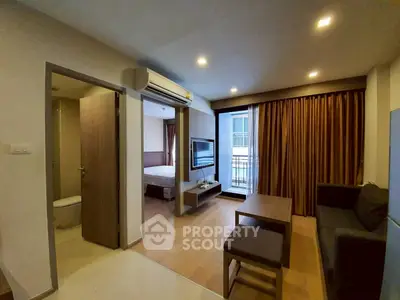 Modern apartment interior with open living room and bedroom, featuring sleek furniture and large windows.