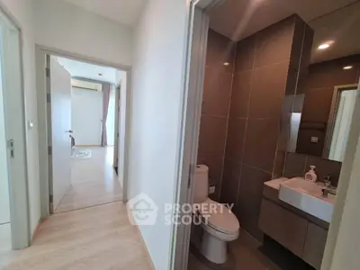 Modern apartment hallway with bathroom and bedroom view, featuring sleek design and natural lighting.