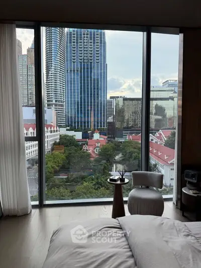 Luxurious bedroom with stunning city view through floor-to-ceiling windows.