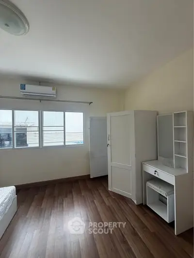 Spacious bedroom with wooden flooring and ample natural light
