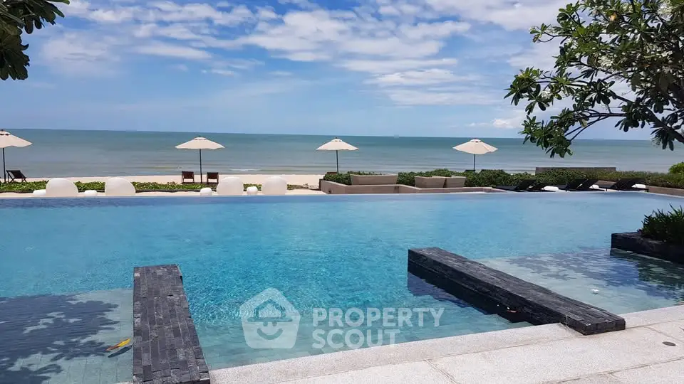 Luxurious beachfront infinity pool with stunning ocean view and elegant lounge chairs.