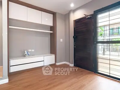 Modern living room with wooden flooring and stylish built-in storage unit.