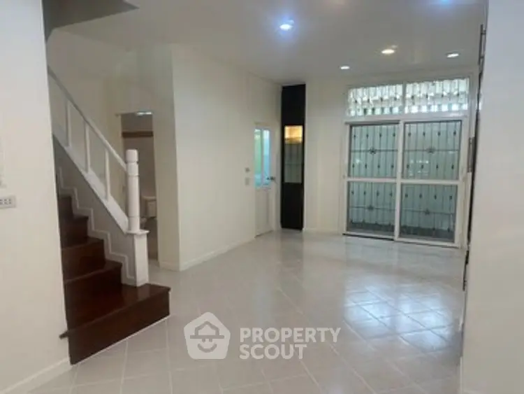 Spacious open-plan living area with tiled flooring and staircase