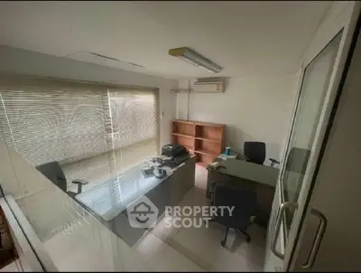 Compact office space with glass door and window blinds, featuring two desks and chairs.