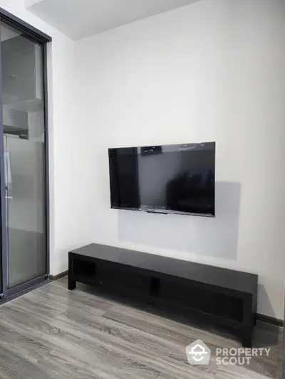 Modern living room with sleek wall-mounted TV and minimalist black TV stand.