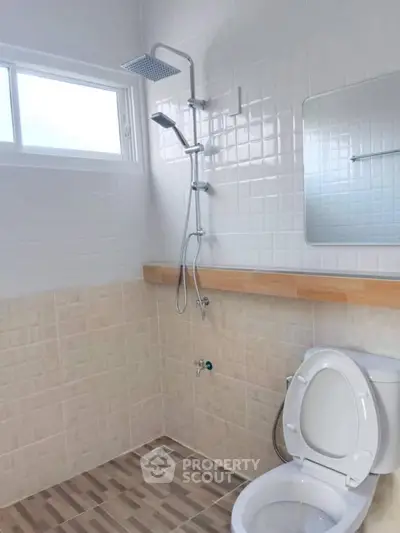 Modern bathroom with sleek shower and toilet in bright, tiled space.