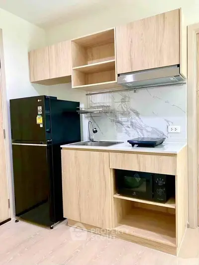 Modern compact kitchen with sleek wooden cabinets and appliances, perfect for urban living.