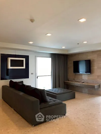 Spacious modern living room with sleek furniture and wall-mounted TV, perfect for relaxation and entertainment.
