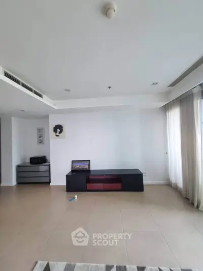 Spacious modern living room with minimalist decor and ample natural light.