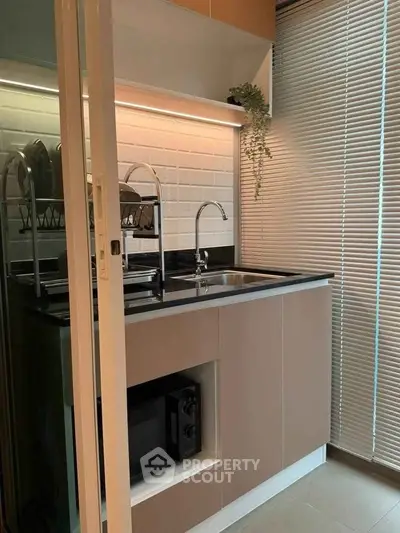 Modern compact kitchen with sleek cabinetry and built-in microwave