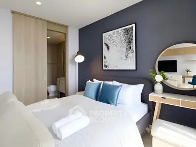 Modern bedroom with stylish decor, featuring a cozy bed, elegant artwork, and a sleek vanity mirror.