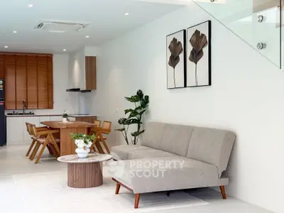 Modern living room with stylish furniture and open kitchen layout, featuring elegant decor and natural light.
