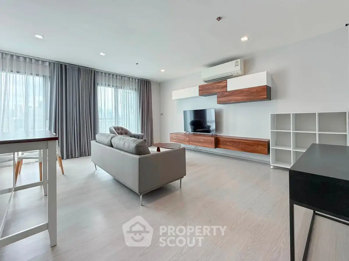 Spacious modern living room with sleek furniture and large windows offering natural light.