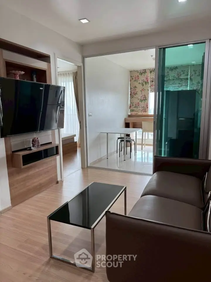 Modern living room with sleek furniture and open layout leading to dining area.