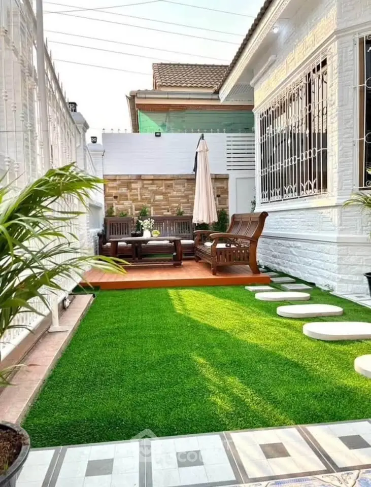 Charming outdoor garden with seating area and lush artificial grass, perfect for relaxation and entertaining.