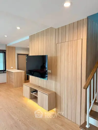 Modern living room with wooden paneling and mounted TV, featuring sleek design and ambient lighting.