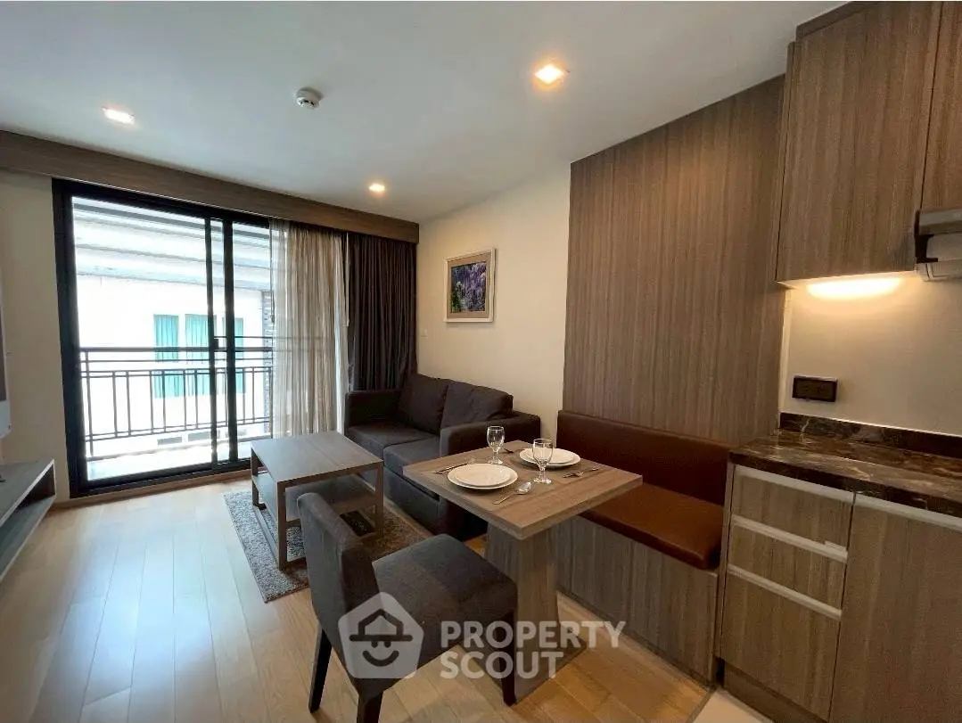 Modern living room with open kitchen and balcony view in stylish apartment.