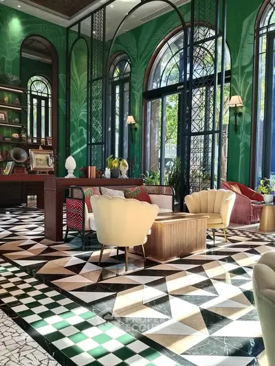 Luxurious living room with elegant decor and vibrant green walls, featuring plush seating and geometric flooring.