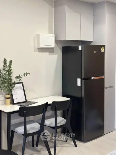 Modern kitchen corner with sleek black fridge and minimalist dining setup.