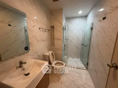 Modern bathroom with marble walls and glass shower enclosure