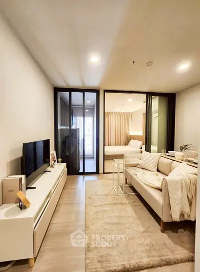 Modern living room with cozy sofa and TV, open view to bedroom