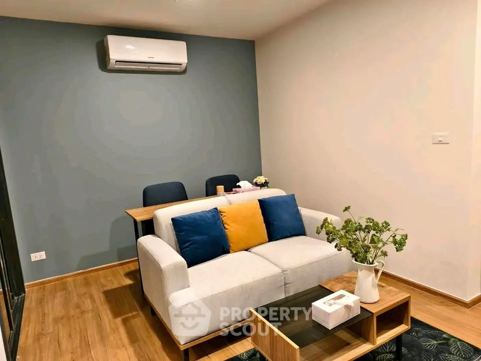 Modern living room with stylish sofa, air conditioning, and wooden flooring for a cozy ambiance.