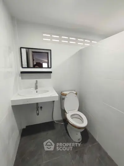 Modern minimalist bathroom with sleek white tiles and contemporary fixtures.