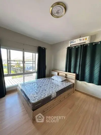 Bright bedroom with large windows and modern air conditioning unit, featuring a comfortable bed.
