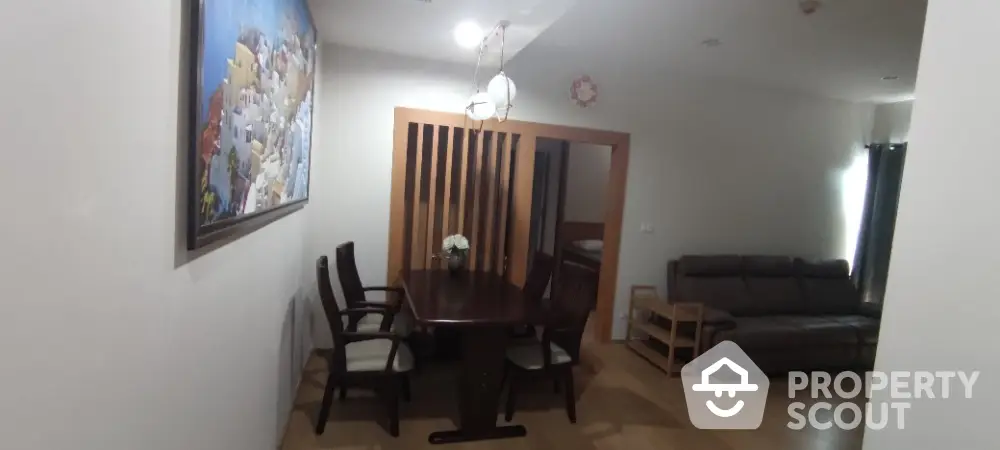 Cozy dining area with elegant wooden table and chairs, adjacent to a comfortable living space.