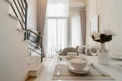 Elegant modern living room with dining area and staircase, featuring high ceilings and natural light.