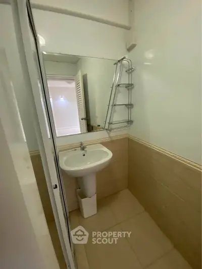 Compact bathroom with pedestal sink and wall-mounted shelf