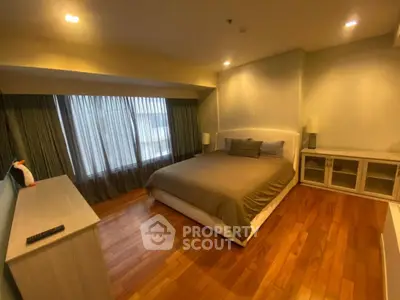 Spacious bedroom with wooden flooring and large window for natural light.