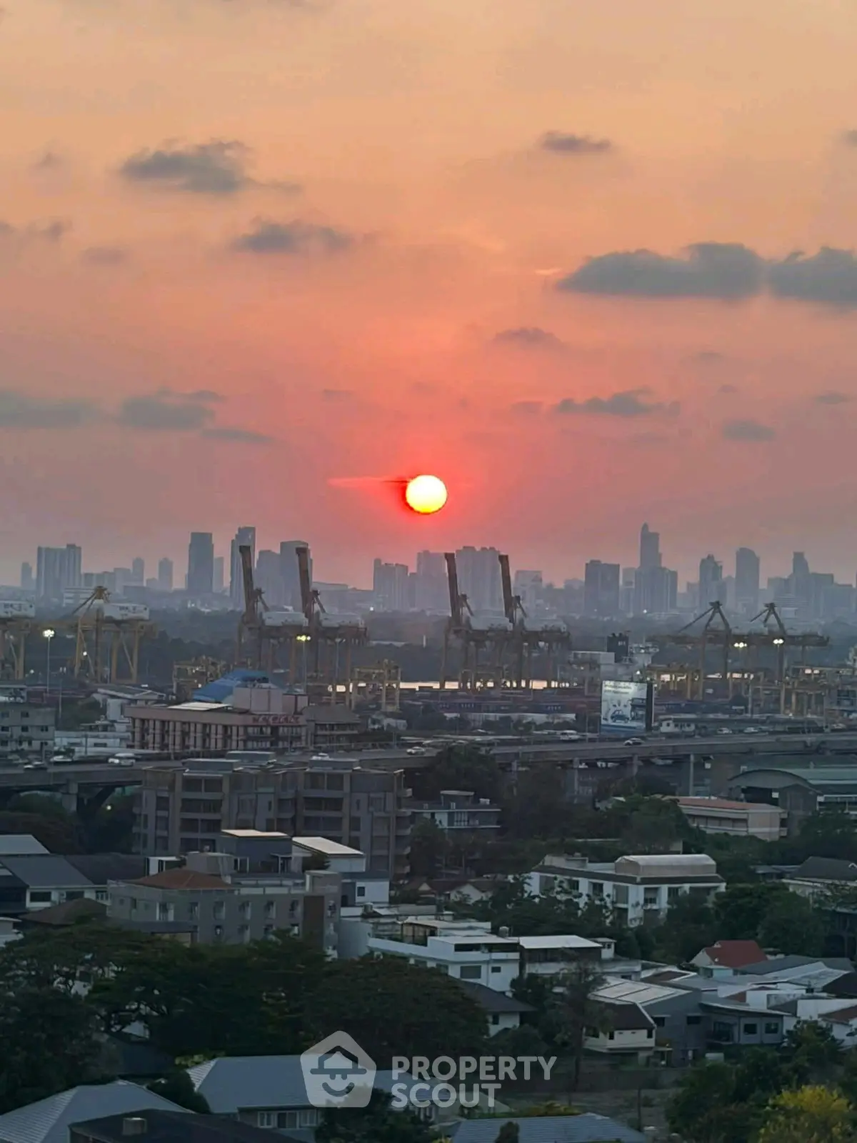 Stunning cityscape view with sunset over urban skyline and industrial cranes.