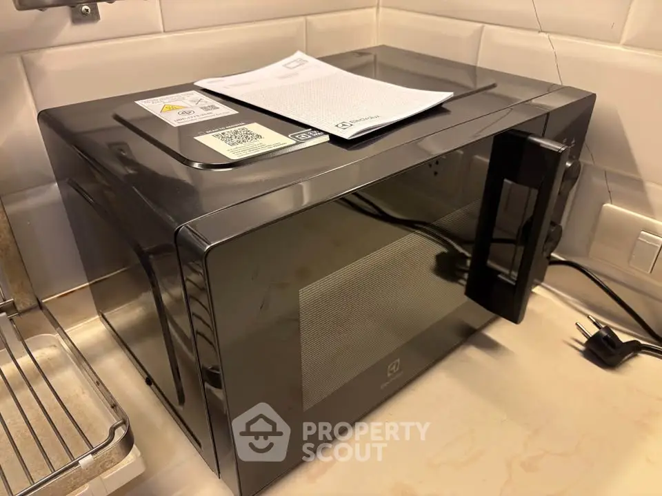 Modern kitchen with sleek black microwave on countertop, showcasing contemporary design and functionality.