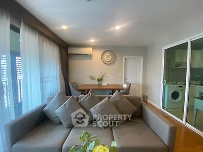 Modern living room with cozy sofa, dining area, and view into kitchen with washing machine.