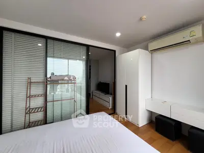 Modern bedroom with balcony view, sleek furniture, and air conditioning unit.