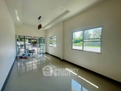 Spacious living room with large windows and glossy floors, perfect for natural light lovers.