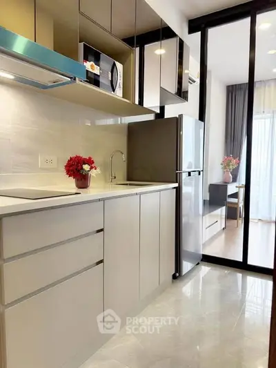 Modern kitchen with sleek cabinets, stainless steel fridge, and microwave in a stylish apartment.
